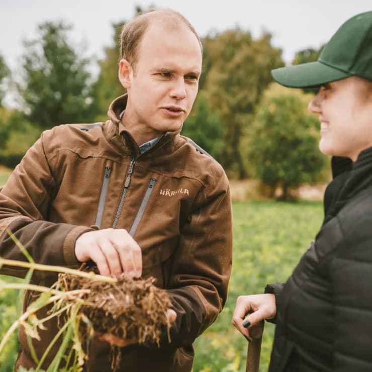 Two farmers inspecting soil in a regenerative field with Klim